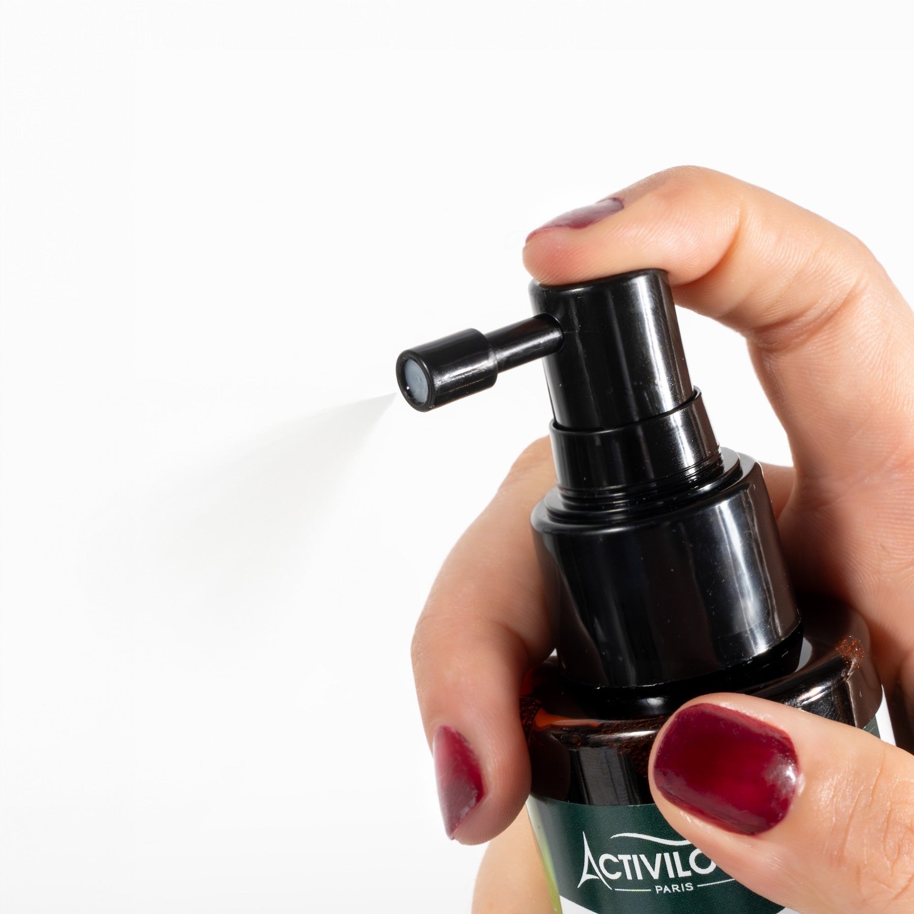 Hand holding a black pump bottle with 'Activilin' branding on a white background by ABS France Wholesale