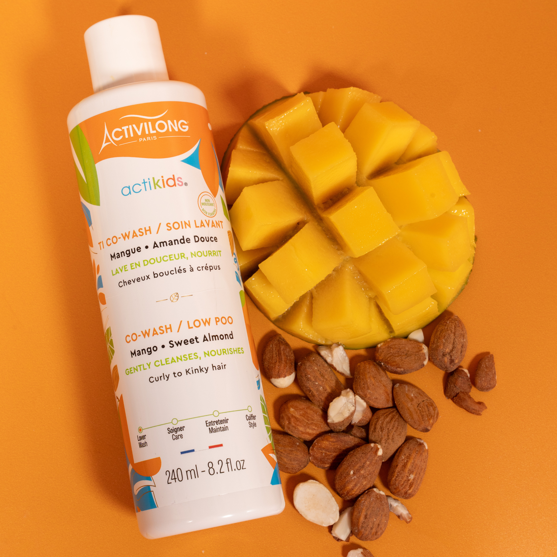ACTIVILONG ACTIKIDS TI Co-Wash Soin Lavant 240ml bottle by ABS France Wholesale with a sliced mango and almonds on an orange background