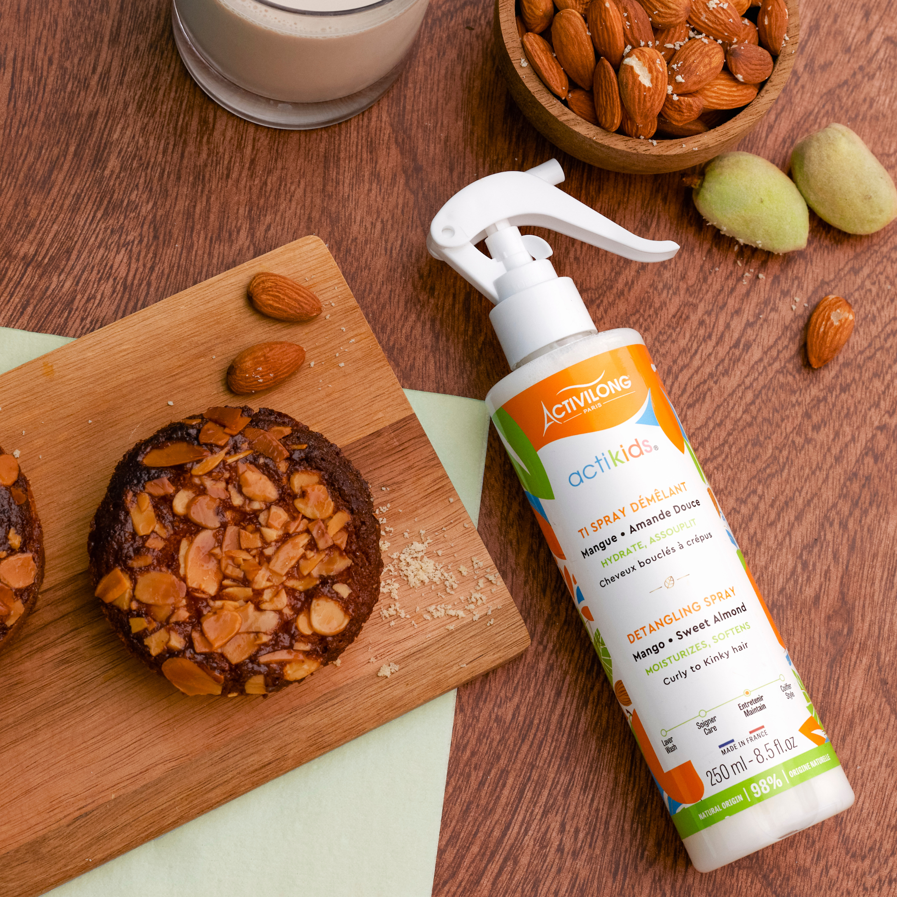 ACTIVILONG ACTIKIDS Ti Spray Démêlant 250ml bottle by ABS France Wholesale on a wooden surface with cookies and almonds.