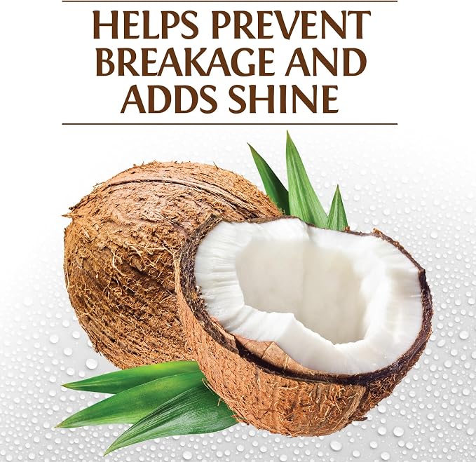 A promotional graphic with the text 'HELPS PREVENT BREAKAGE AND ADDS SHINE' above a cut coconut showing white flesh and green leaves on a white water-droplet background.