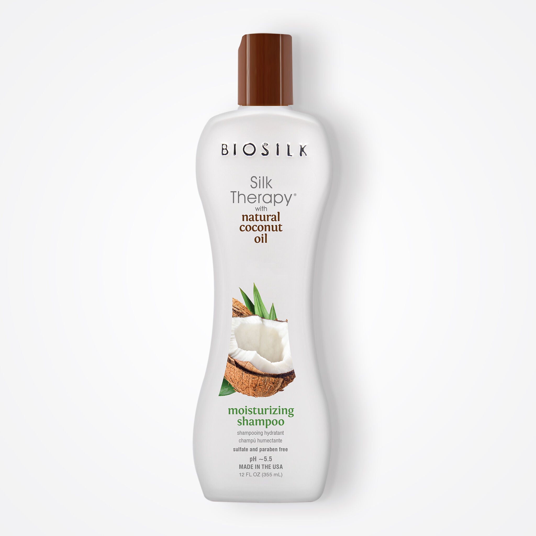 A bottle of BIOSILK Silk Therapy moisturizing shampoo with natural coconut oil, featuring a white bottle, brown cap, and a graphic of a coconut on a light gray background.