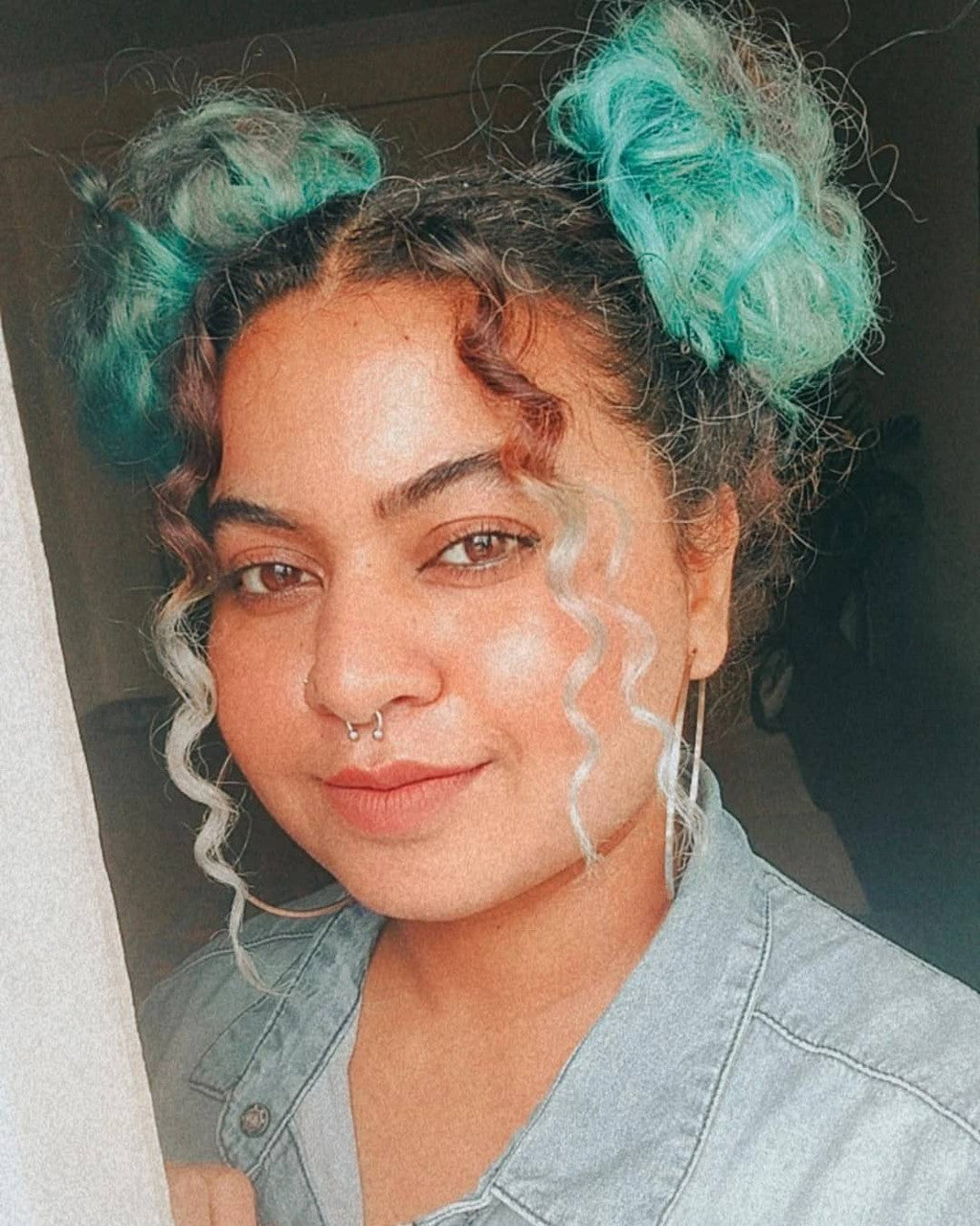 Crazy Color's Person with teal hair extensions styled in buns, wearing a denim shirt by ABS France Wholesale