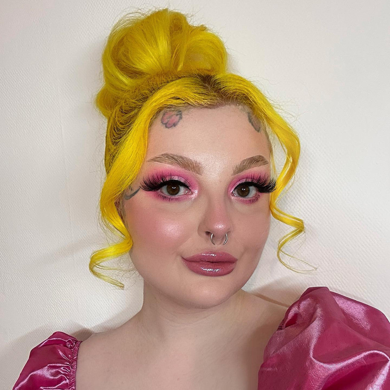 Crazy Color's Person with bright yellow hair and pink makeup wearing a pink top against a white background by ABS France Wholesale