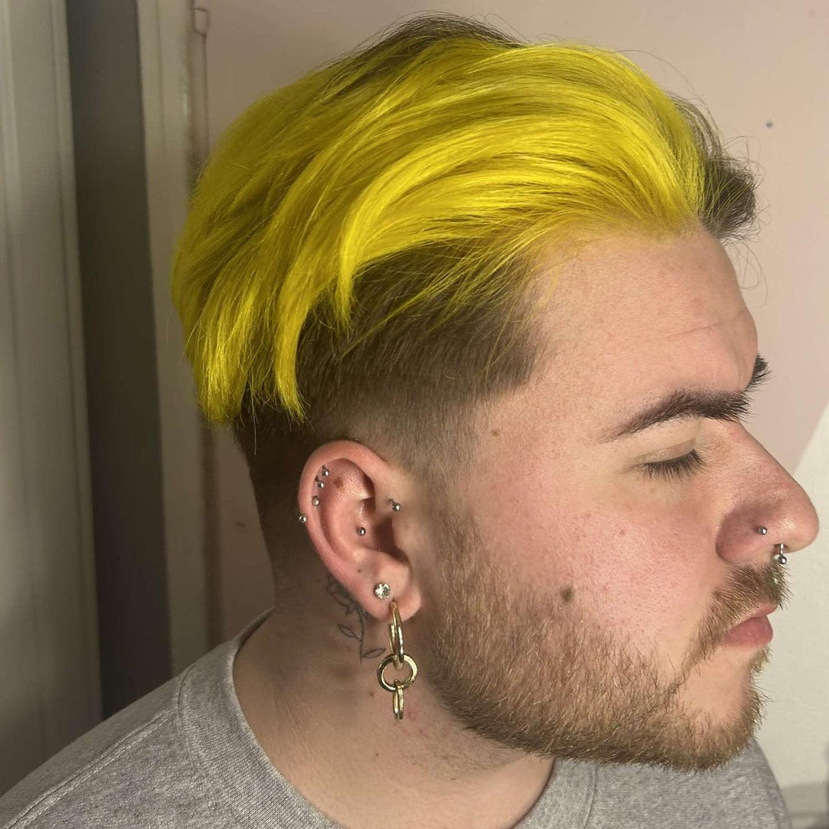 Crazy Color's Person with bright yellow hair and multiple piercings, wearing a gray shirt by ABS France Wholesale
