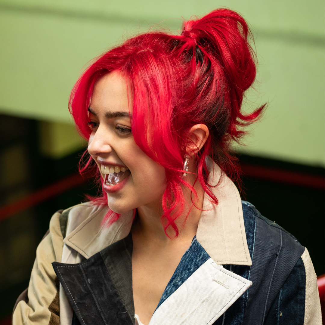 Crazy Color's person with red hair styled in a high ponytail, wearing a denim jacket with a beige collar by ABS France Wholesale
