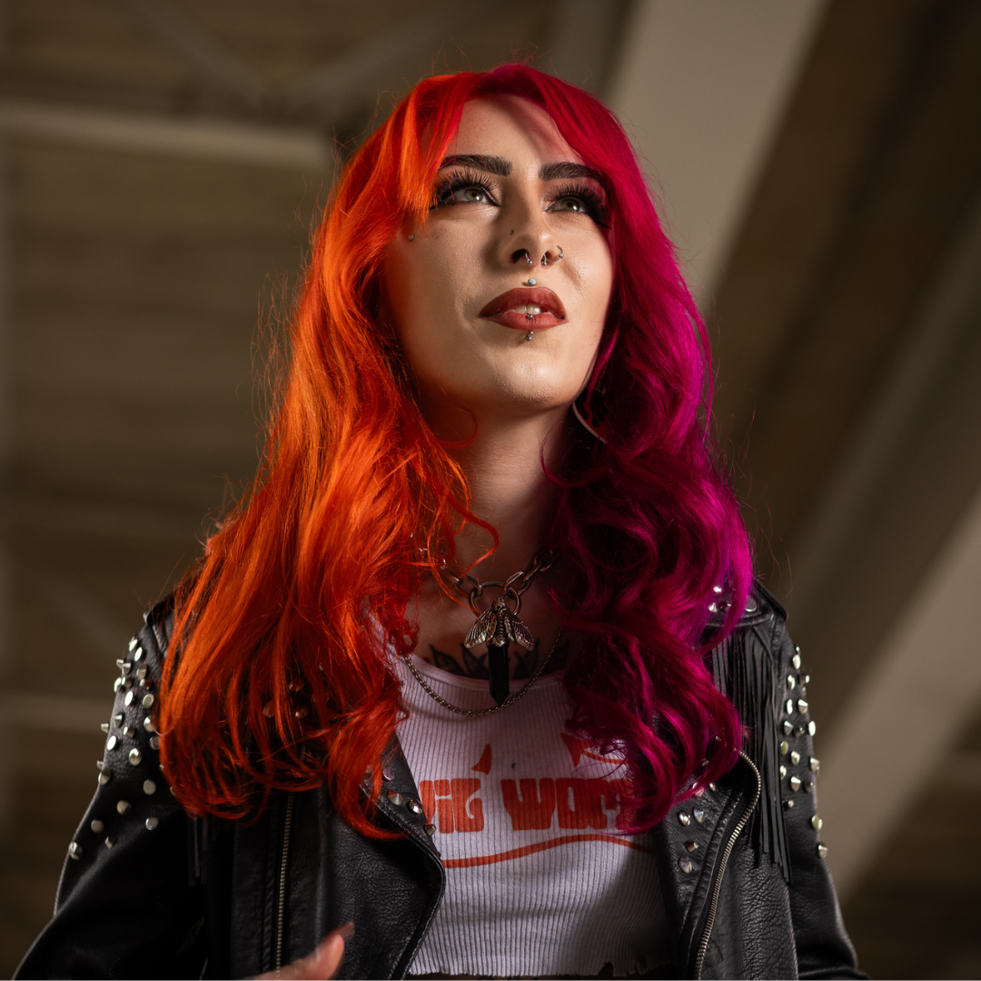 Crazy Color's Person with vibrant red and pink hair wearing a black leather jacket and white t-shirt with text - ABS France Wholesale