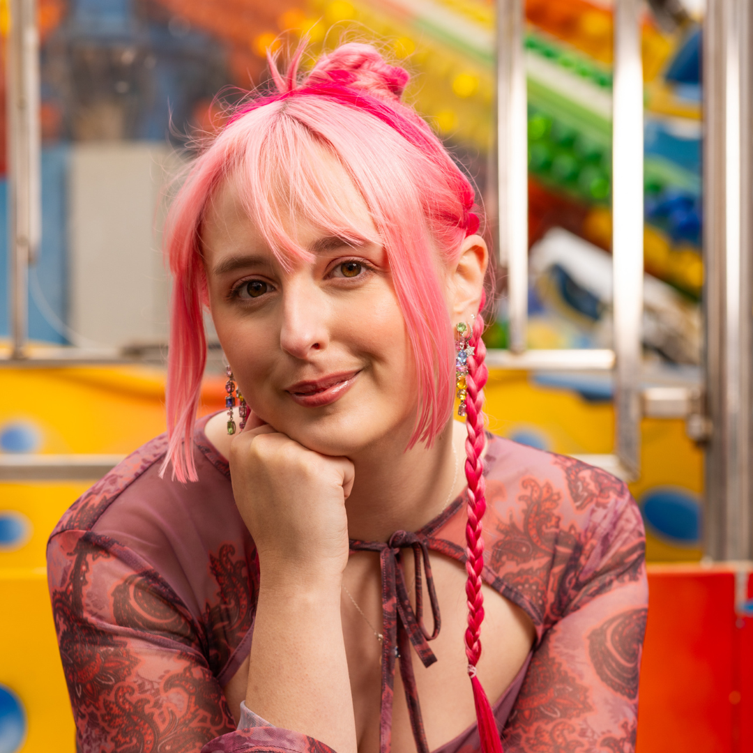 Crazy Color's person with pink hair and braids posing in front of a colorful background by ABS France Wholesale