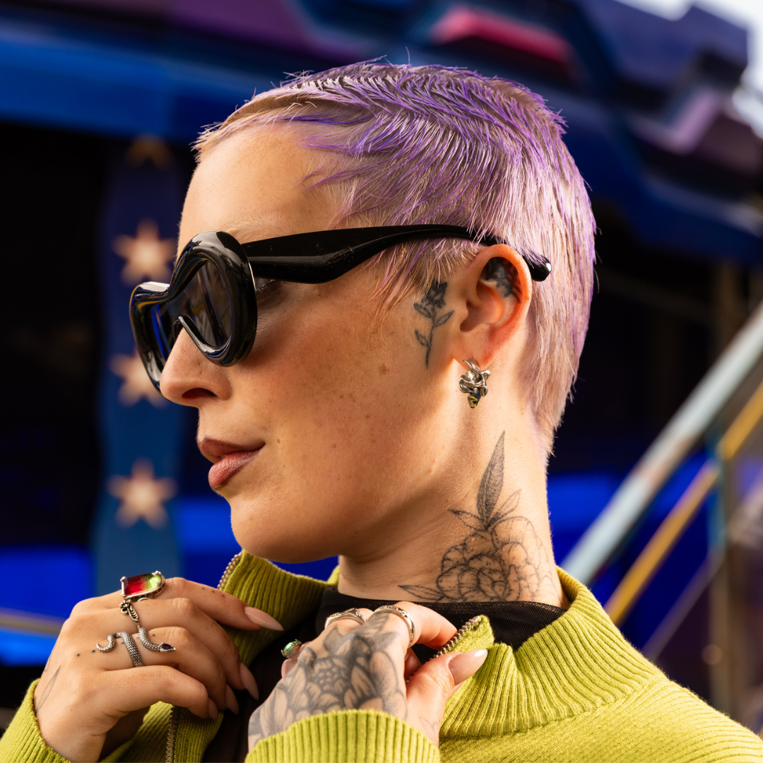 Crazy Color's Person with purple hair and tattoos wearing sunglasses and a green sweater by ABS France Wholesale