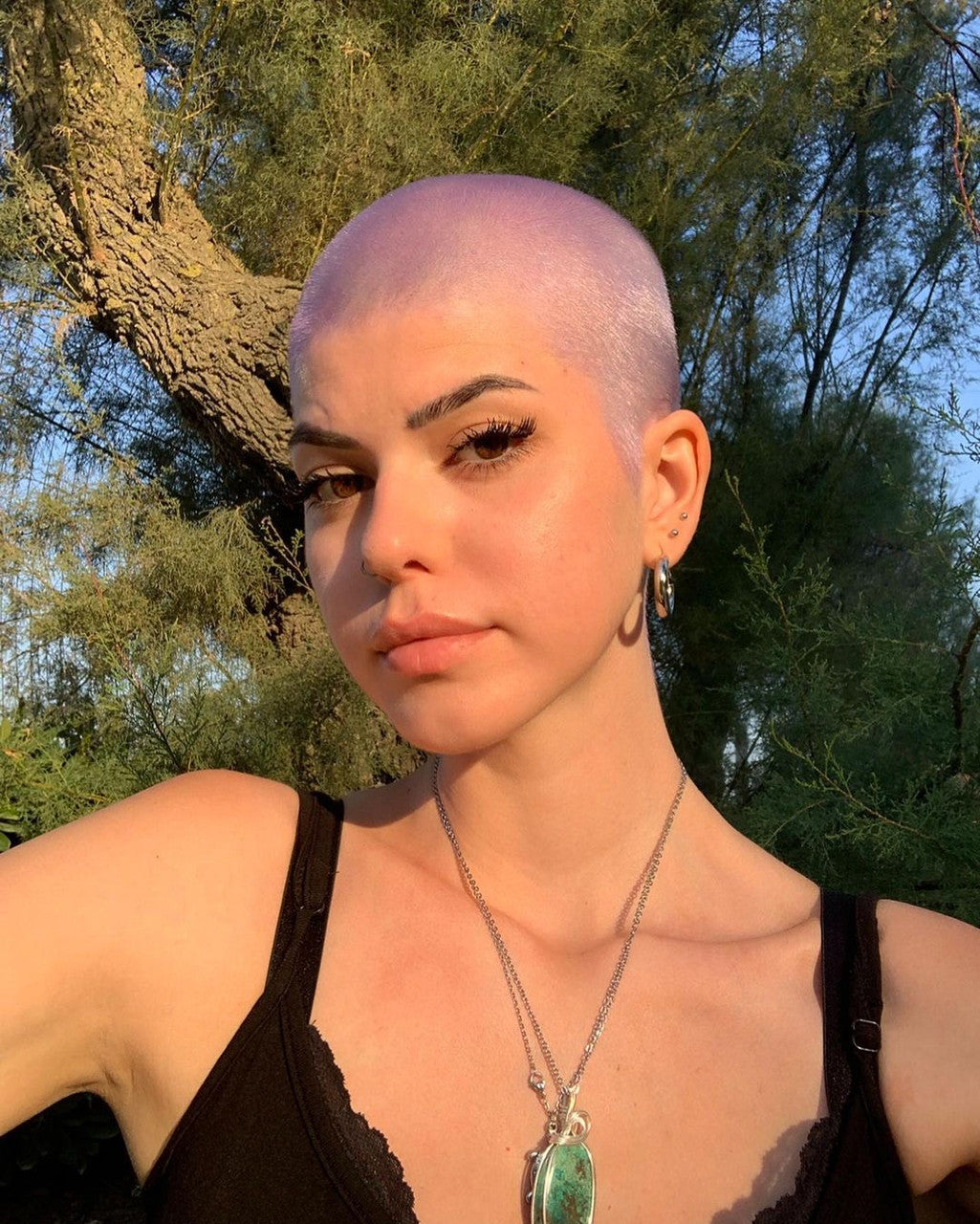Crazy Color's person with a shaved head standing outdoors with trees in the background by ABS France Wholesale