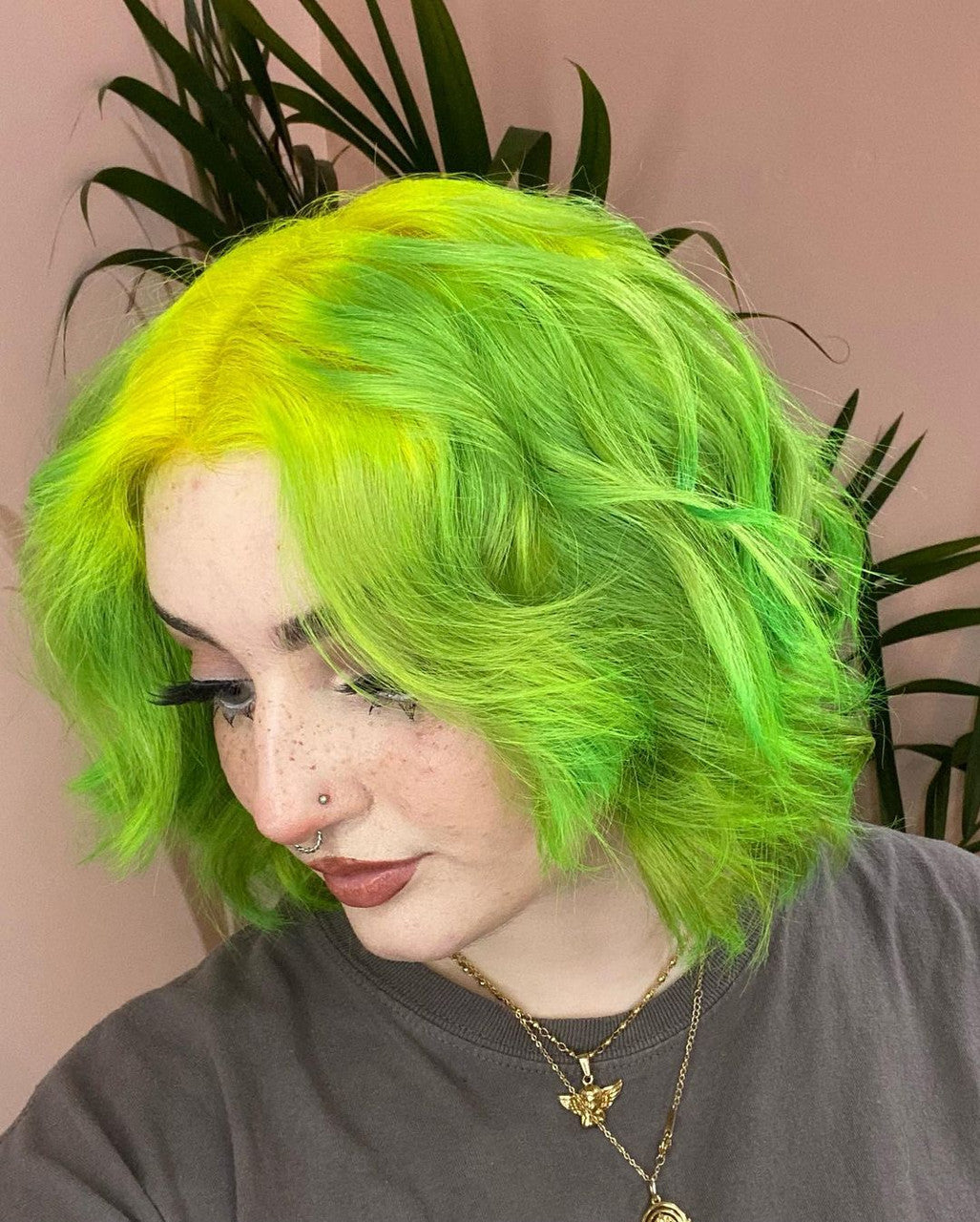 Crazy Color's Person with bright green hair against a pink background with plants by ABS France Wholesale