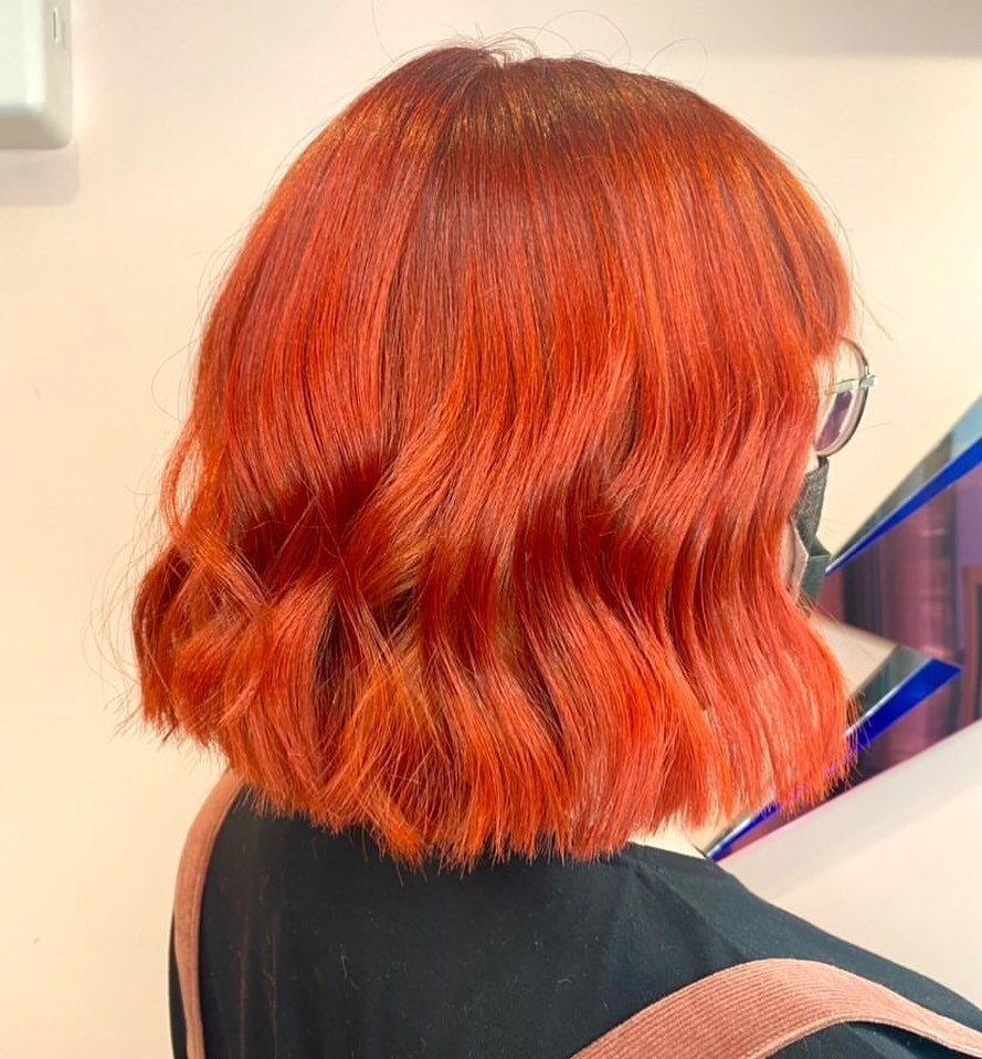 Crazy Color's Person with vibrant orange-red hair in a salon setting by ABS France Wholesale