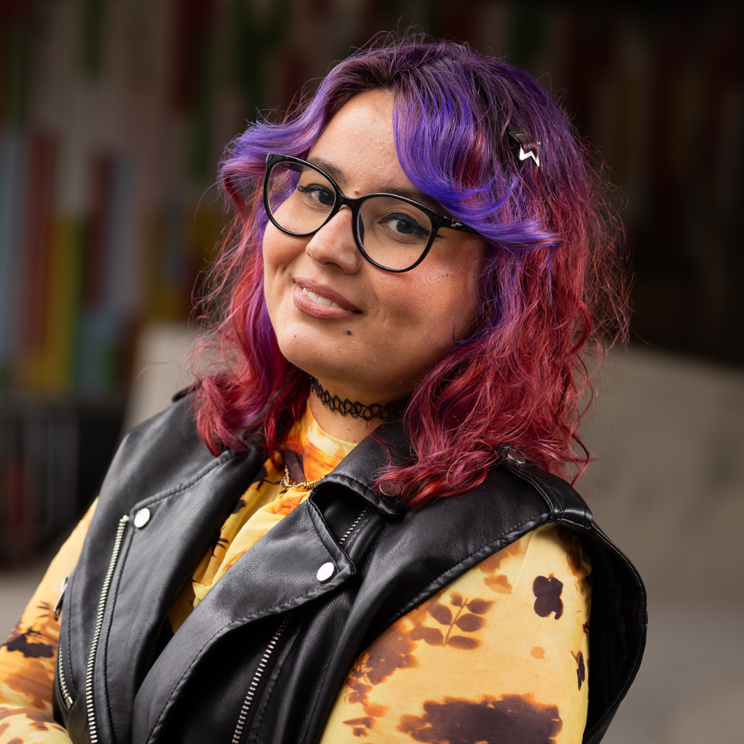 Crazy Color's Person with purple and red hair wearing glasses and a black leather vest over a patterned shirt - ABS France Wholesale
