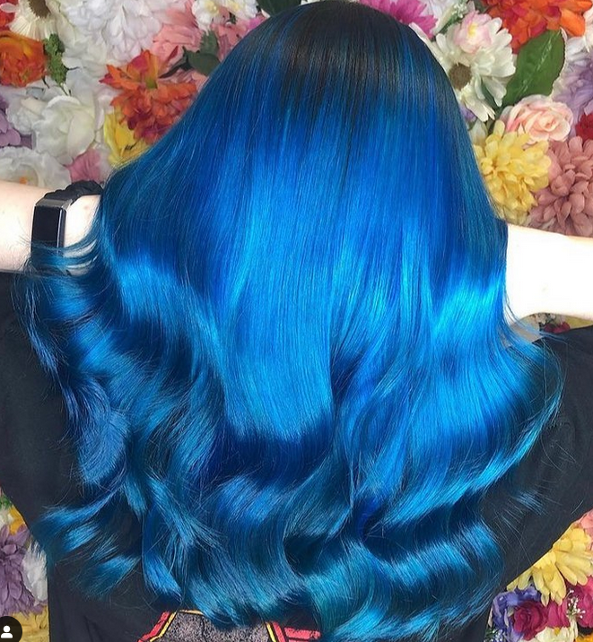 Crazy Color's Person with vibrant blue hair in front of a floral background by ABS France Wholesale