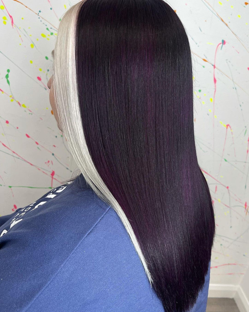 Crazy Color Person wearing a black and white hairpiece against a colorful splatter-painted wall by ABS france Wholesale