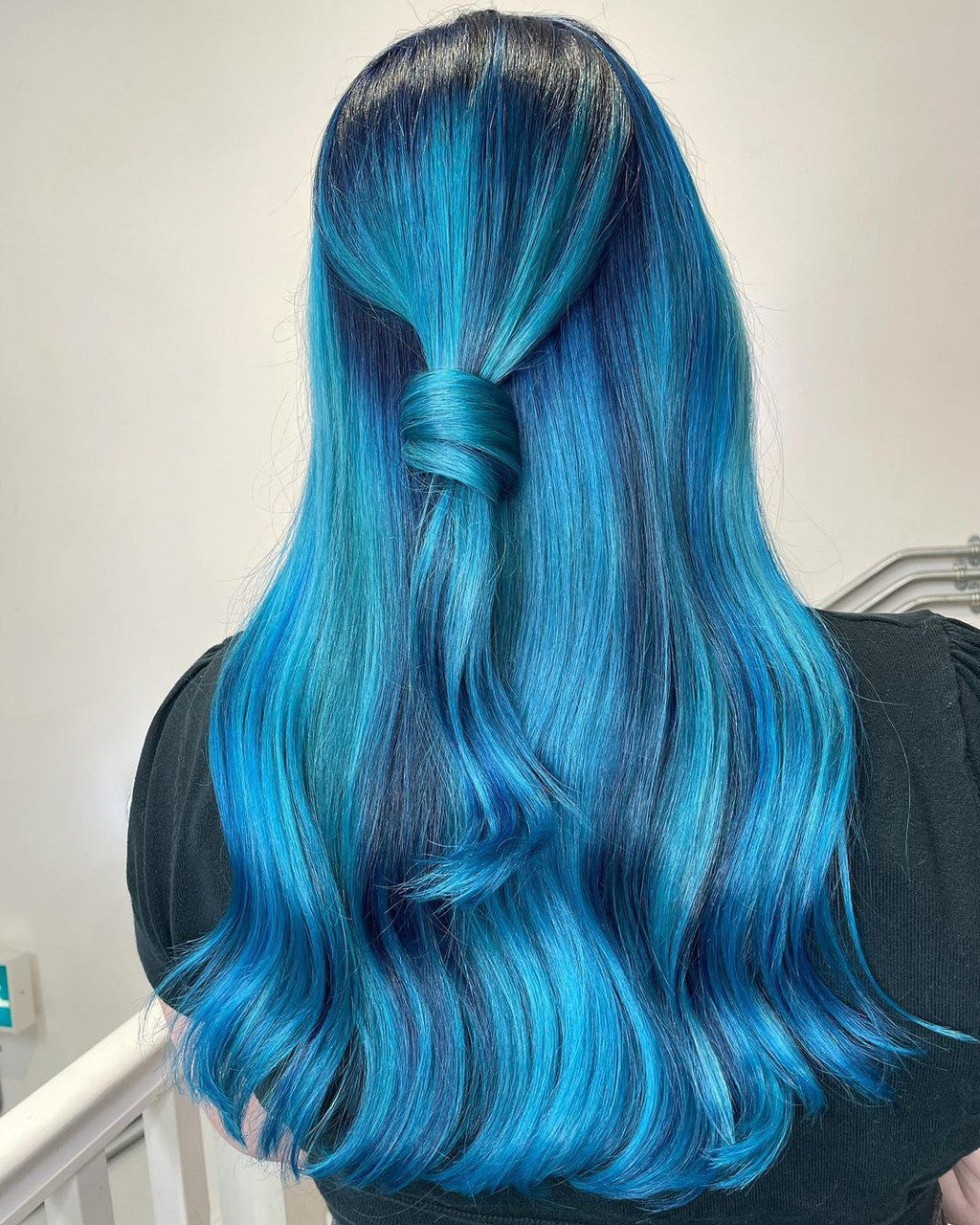 Crazy Color's Person with vibrant blue hair styled in a ponytail against a neutral background by ABS France Wholesale