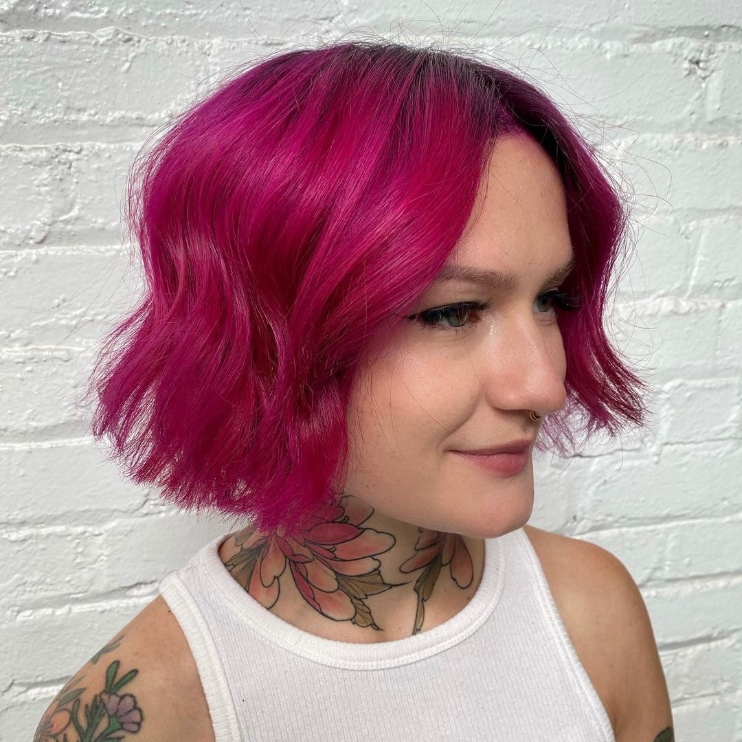 Crazy Color's Person with vibrant pink hair and tattoos against a white brick wall - ABS France Wholesale