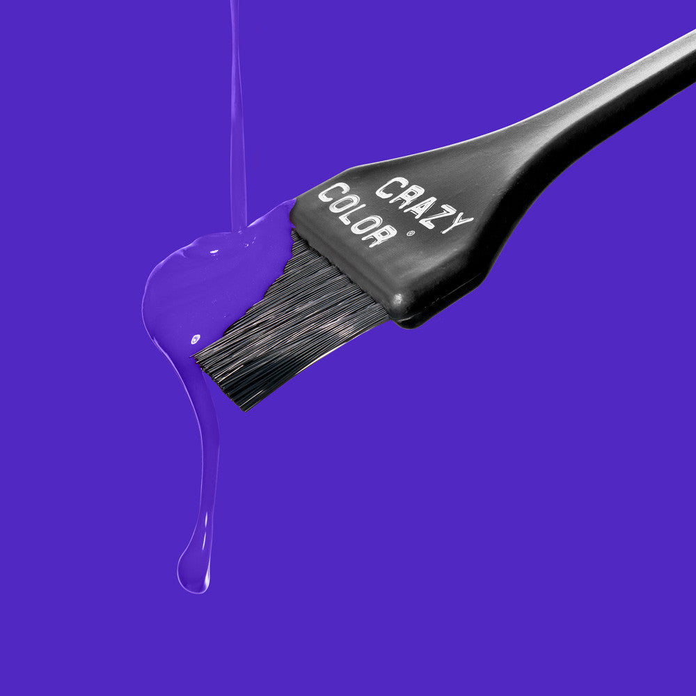 Crazy Color Hair dye brush with purple liquid dripping from it on a blue background by ABS France Wholesale