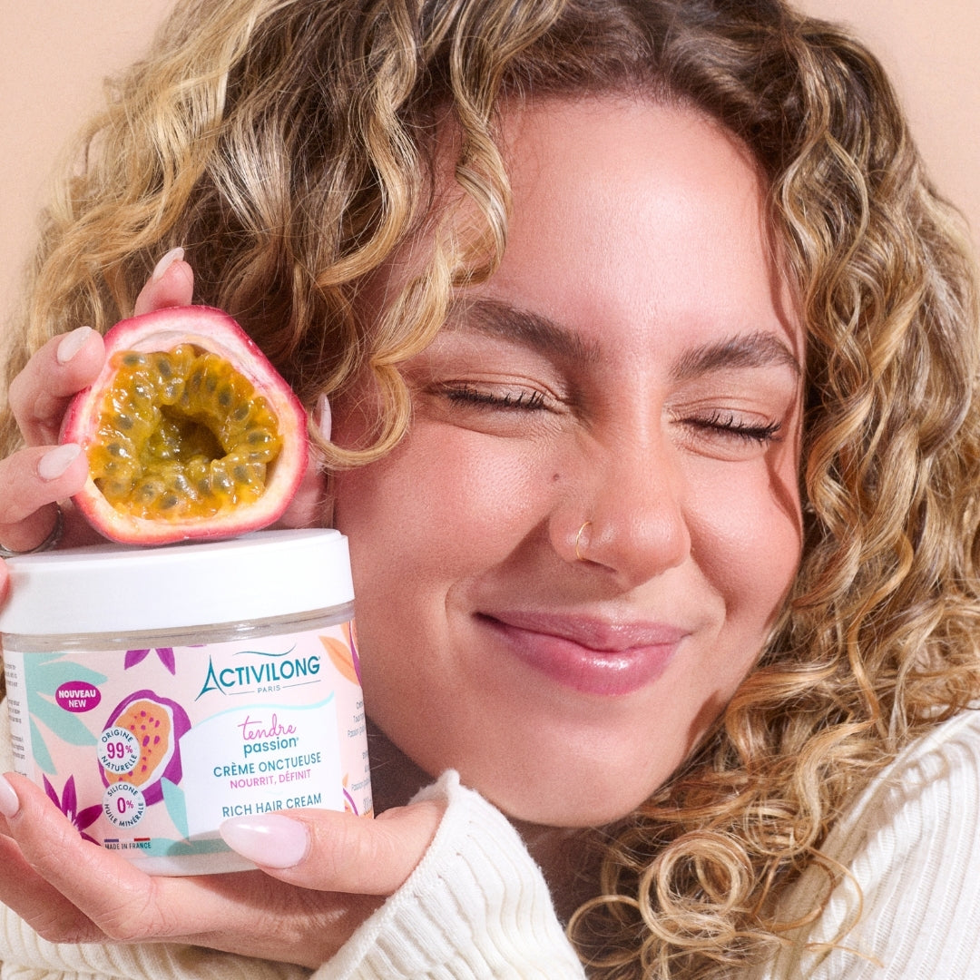 Woman holding a container of ACTIVILONG TENDRE PASSION Crème Onctueuse 300ml by ABS France Wholesale  and a passion fruit