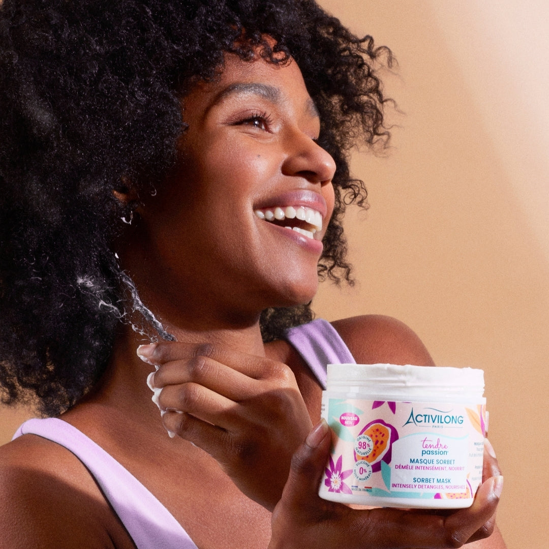 Woman holding an ACTIVILONG TENDRE PASSION Masque Sorbet 300ml jar by ABS France Wholesale against a beige background