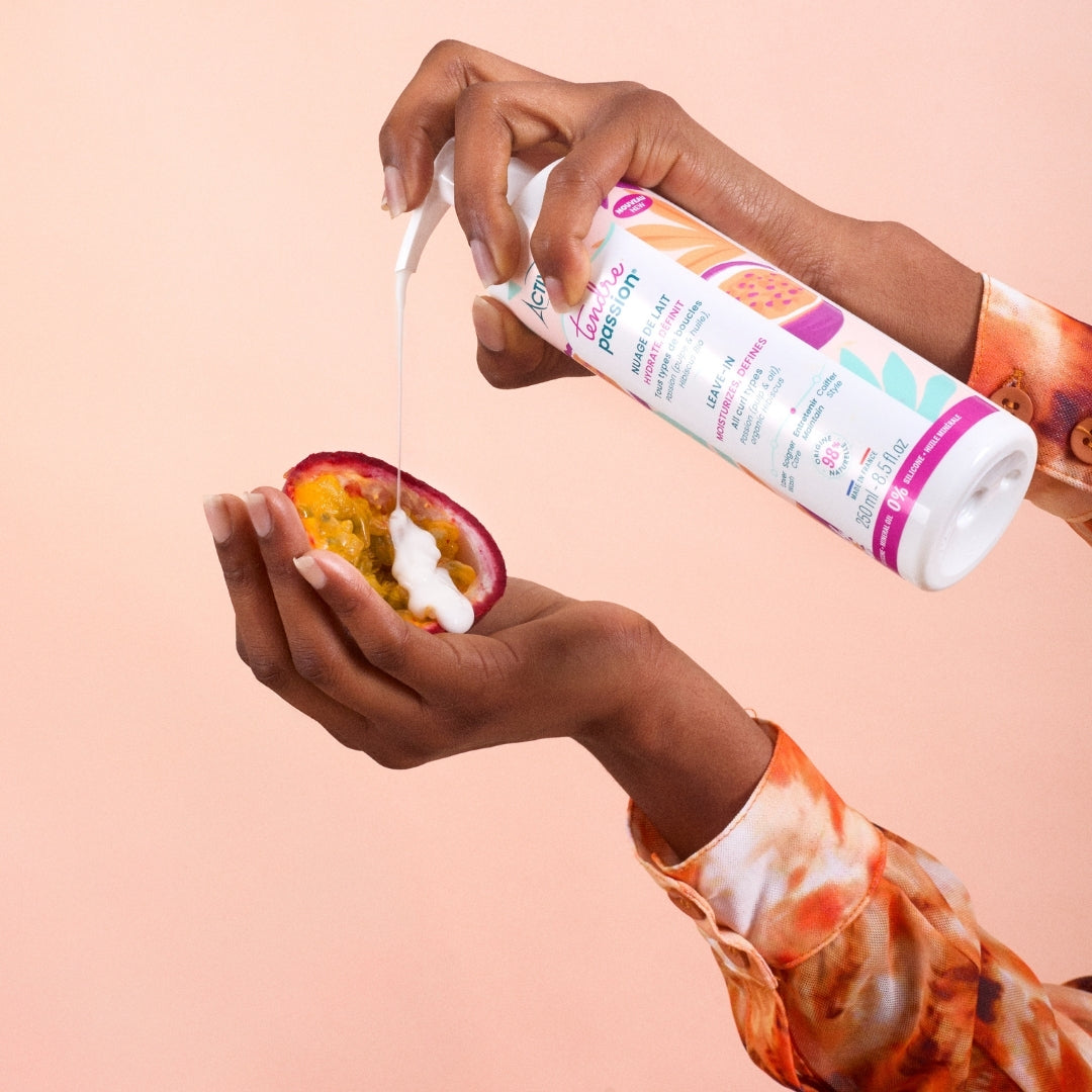 Person using a bottle of ACTIVILONG TENDRE PASSION Nuage de Lait 250ml by ABS France Wholesale on a fruit against a pink background