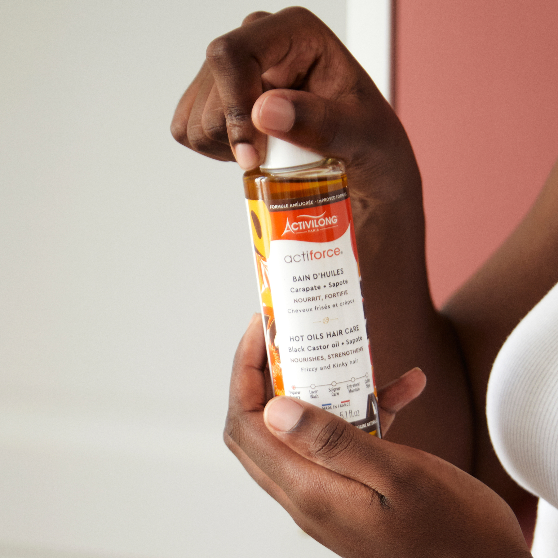 Hand holding an ACTIVILONG ACTIFORCE Bain d'Huile 130ml Bottle by ABS France Wholesale against a neutral background