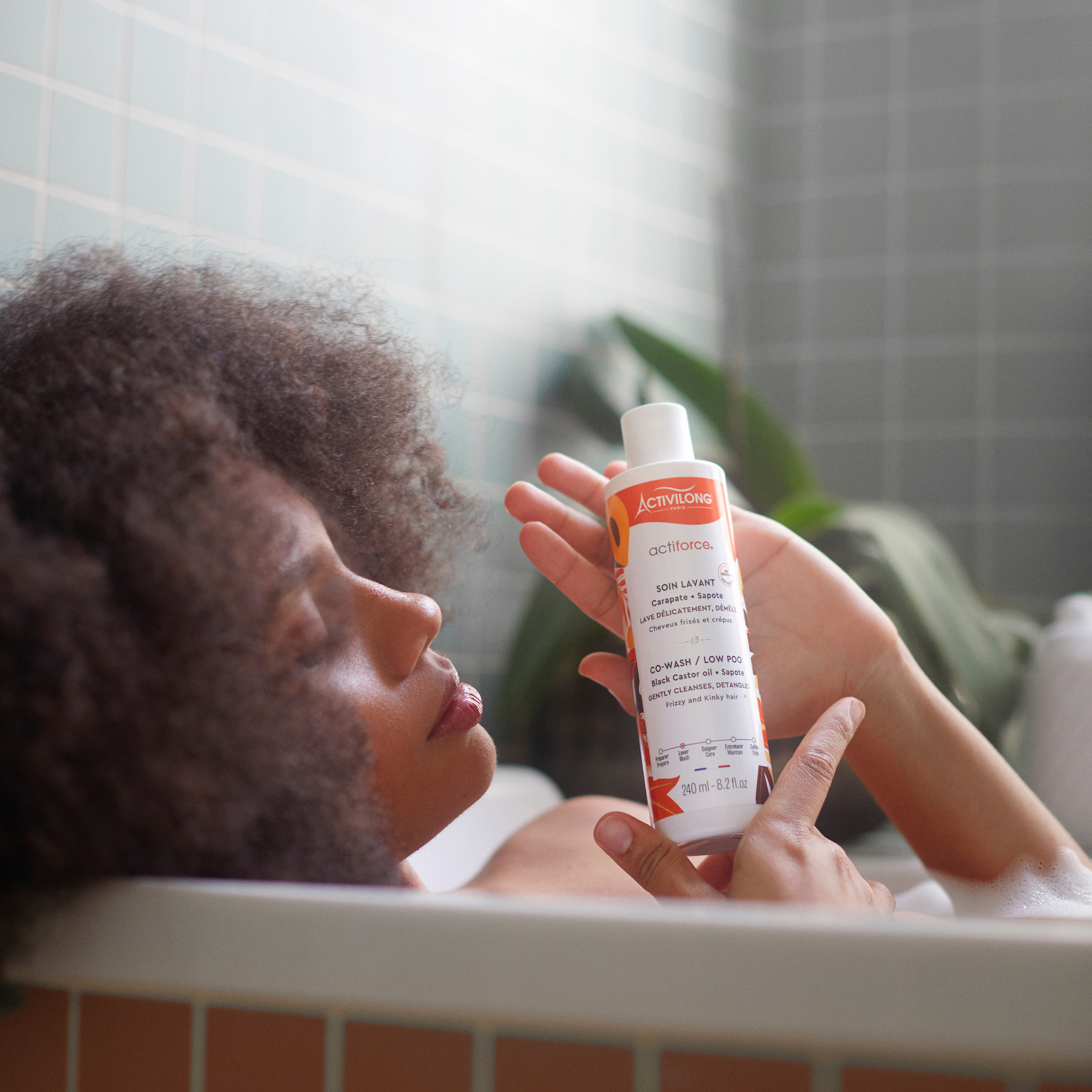 Person in a bathtub holding a Bottle of ACTIVILONG ACTIFORCE Co-wash 240ml by ABS France Wholesale 