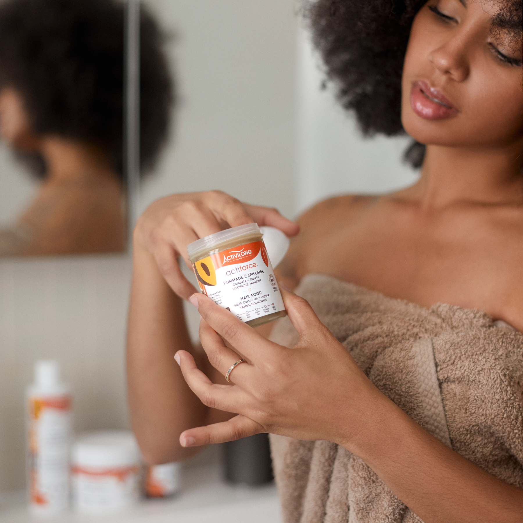 Woman holding an ACTIVILONG ACTIFORCE Pommade Fortifiante 100ml container by ABS France Wholesale