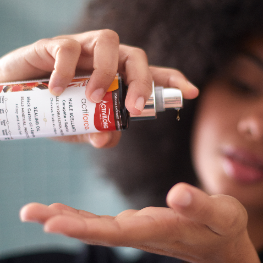 Person applying an ACTIVILONG ACTIFORCE Huile Scellante 125ml bottle by ABS France Wholesale to their palm with a blurred background