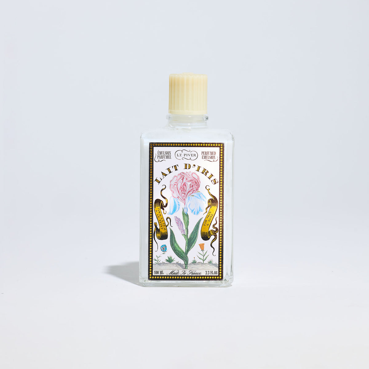 Bottle of Lait d'Iris with decorative label on a light gray background
