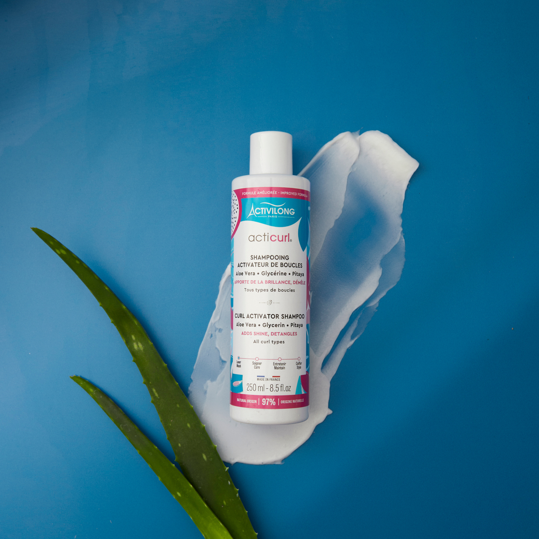 Bottle of ACTIVILONG ACTICURL Shampoing 250ml by ABS France Wholesale with aloe vera leaf on a blue background