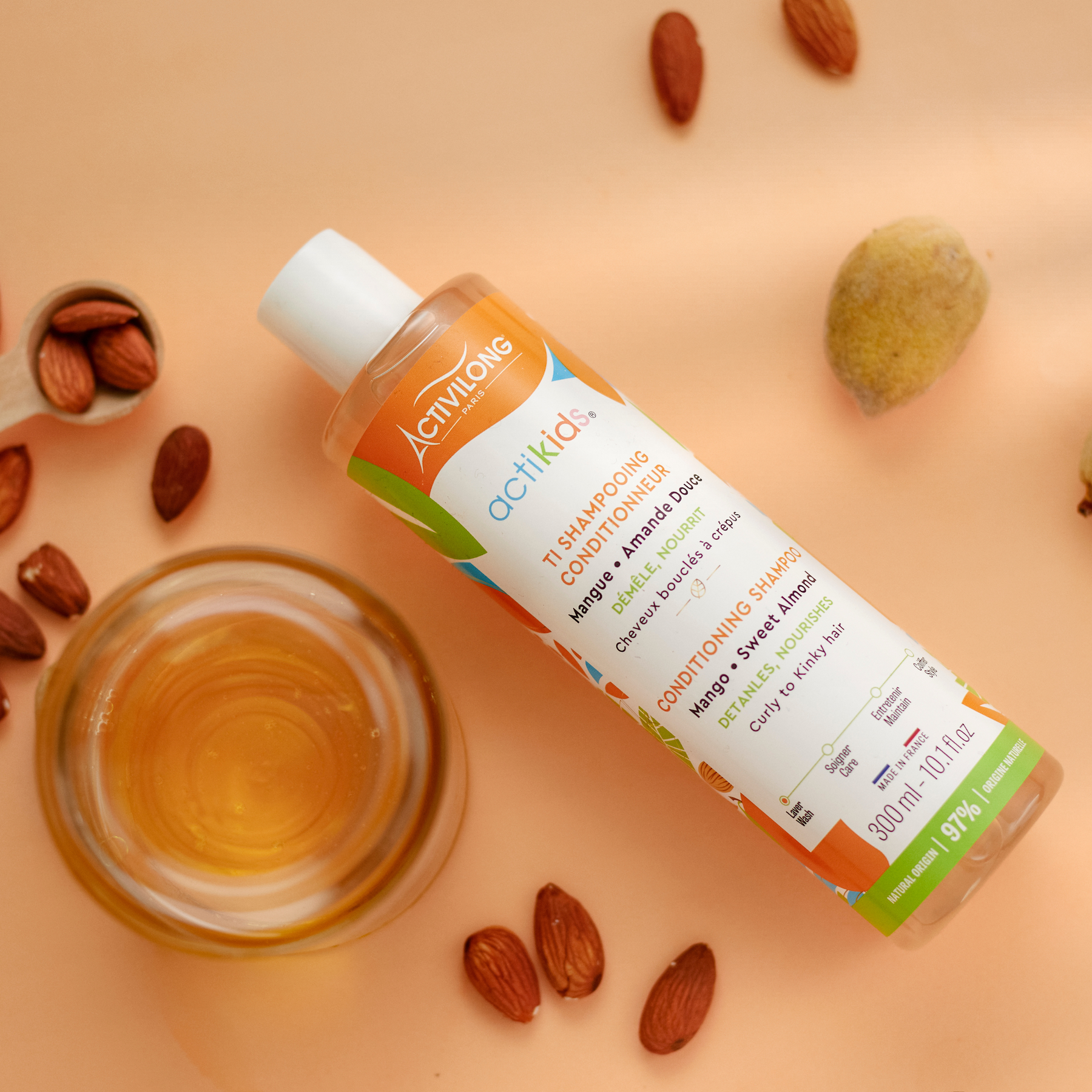 ACTIVILONG ACTIKIDS Ti-Shampooing Conditionneur 250ml bottle by ABS France Wholesale on a peach background with almonds and a small bowl of oil.